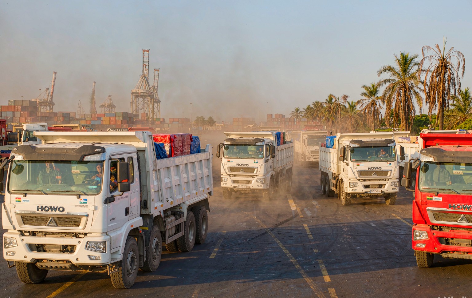 howo-africa-news Fleet of HOWO dump trucks lined up at a port ready for shipment to Africa